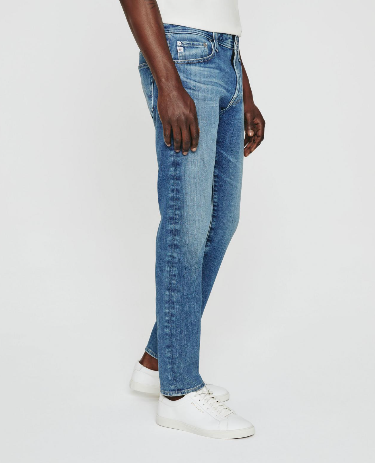 model facing sideways wearing ag jeans dylan slim fit jean in talavera blue, shown from the waist down