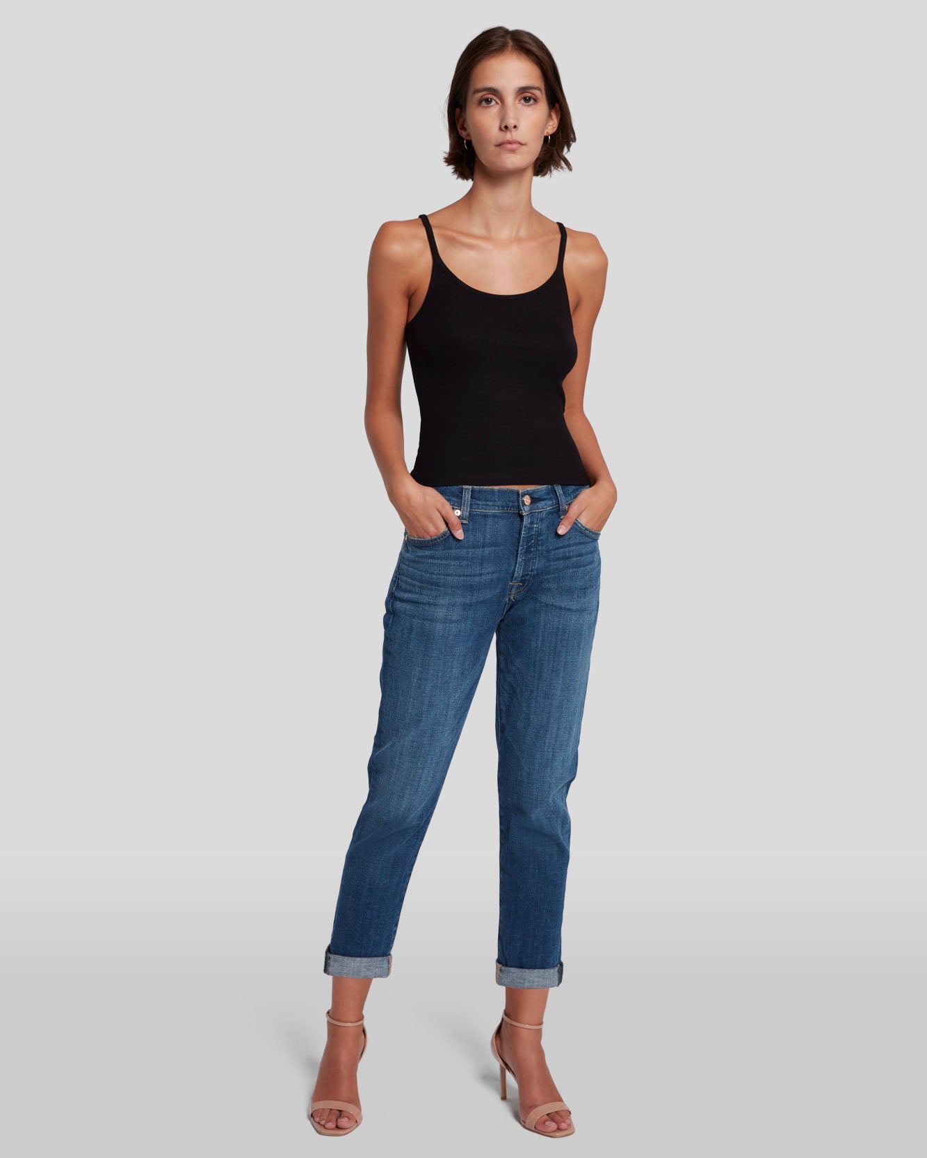 model posing, wearing 7 for all mankind josefina boyfriend fit jean in broken twill vanity blue, paired with a black tank top and sandals
