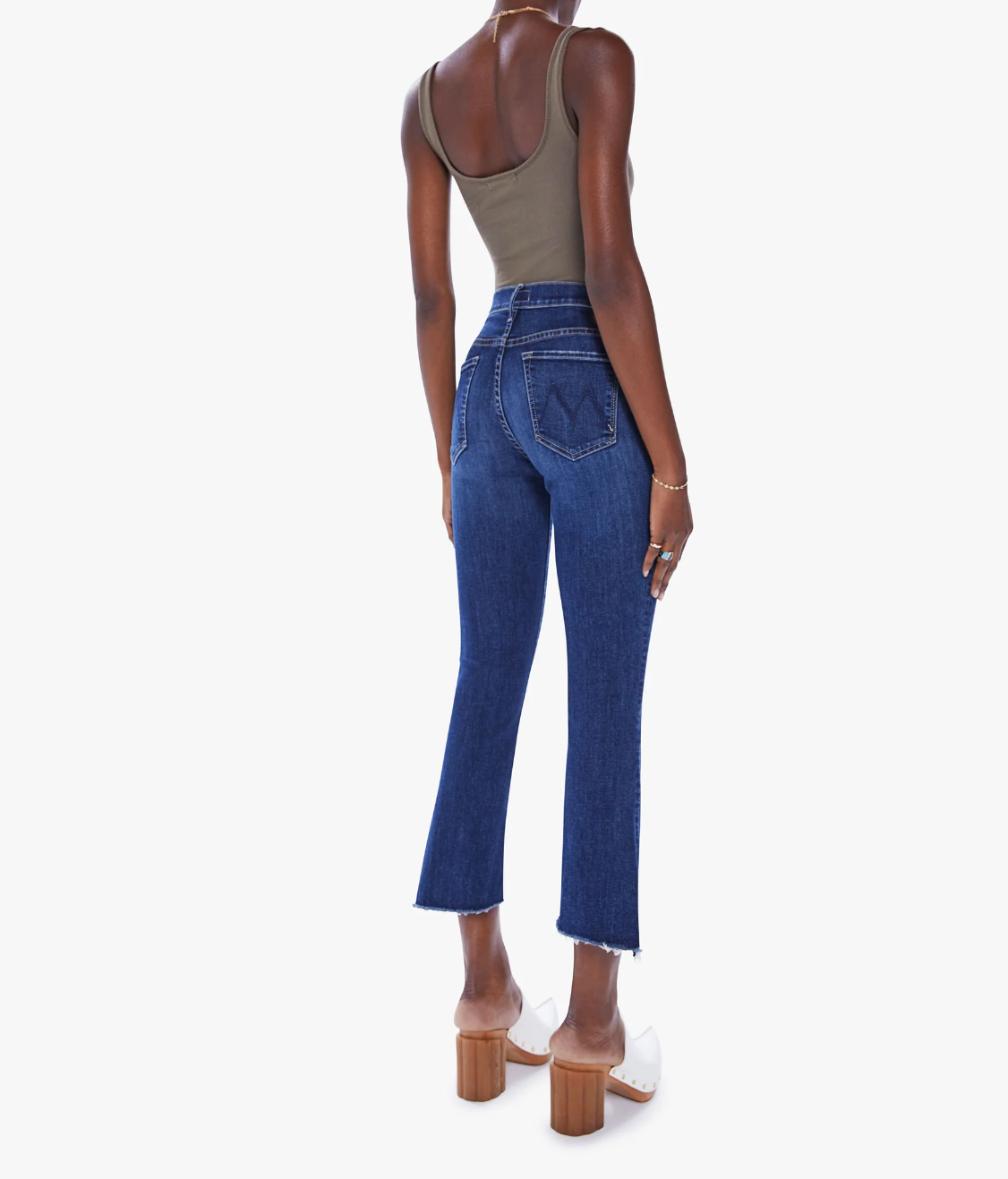 rear view of the insider crop step fray jean from Mother in teaming up blue, styled with an olive green tank top and white clogs