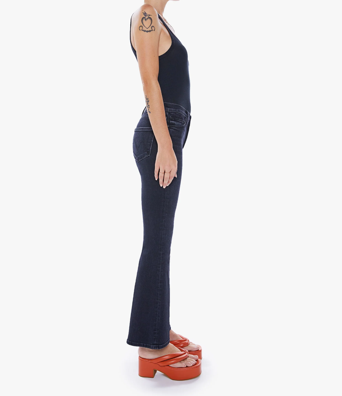 side view of the weekender flare jean in deep end black, styled with a black tank and orange sandals