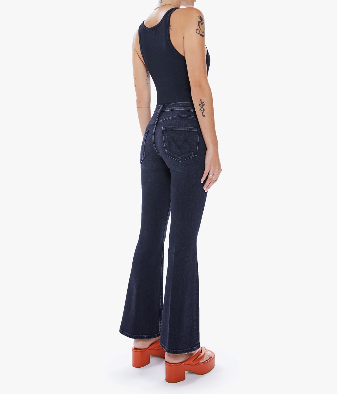 rear view of the weekender flare jean in deep end black, styled with a black tank and orange sandals