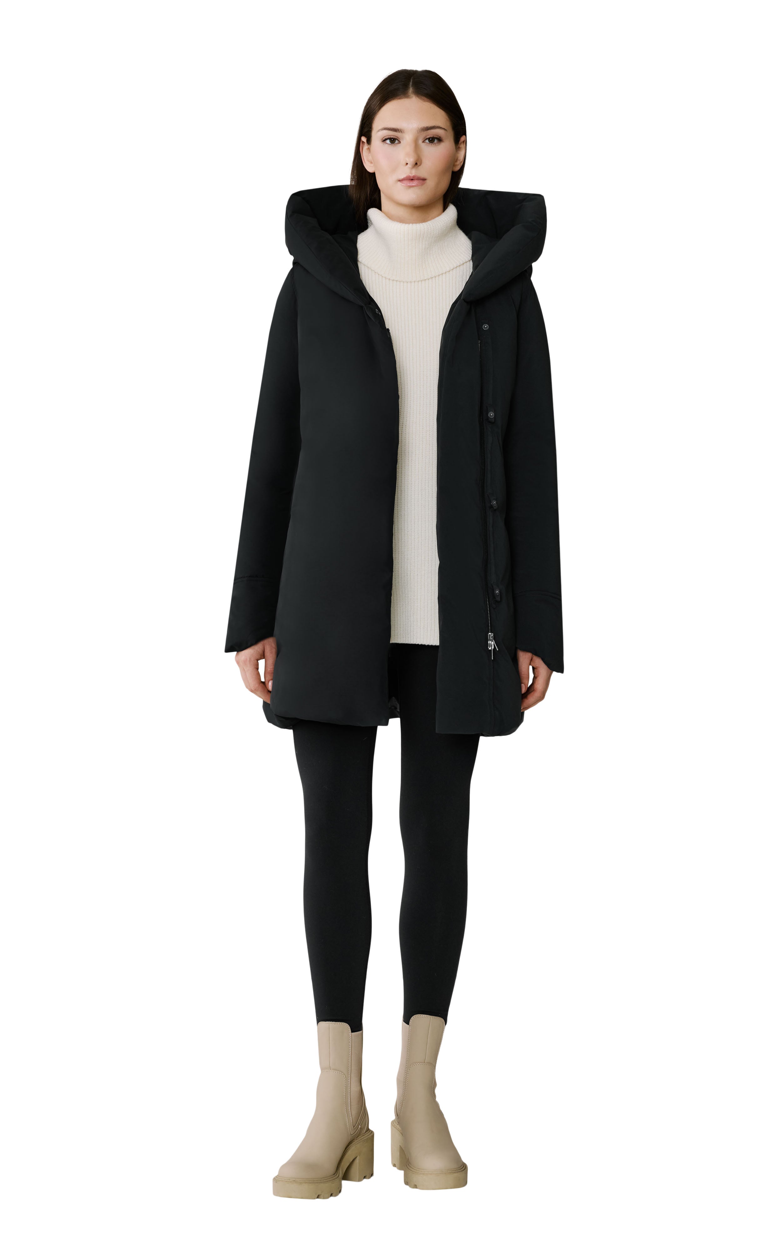 Woman wearing a black coat, white sweater, black leggings, and beige boots on a white background