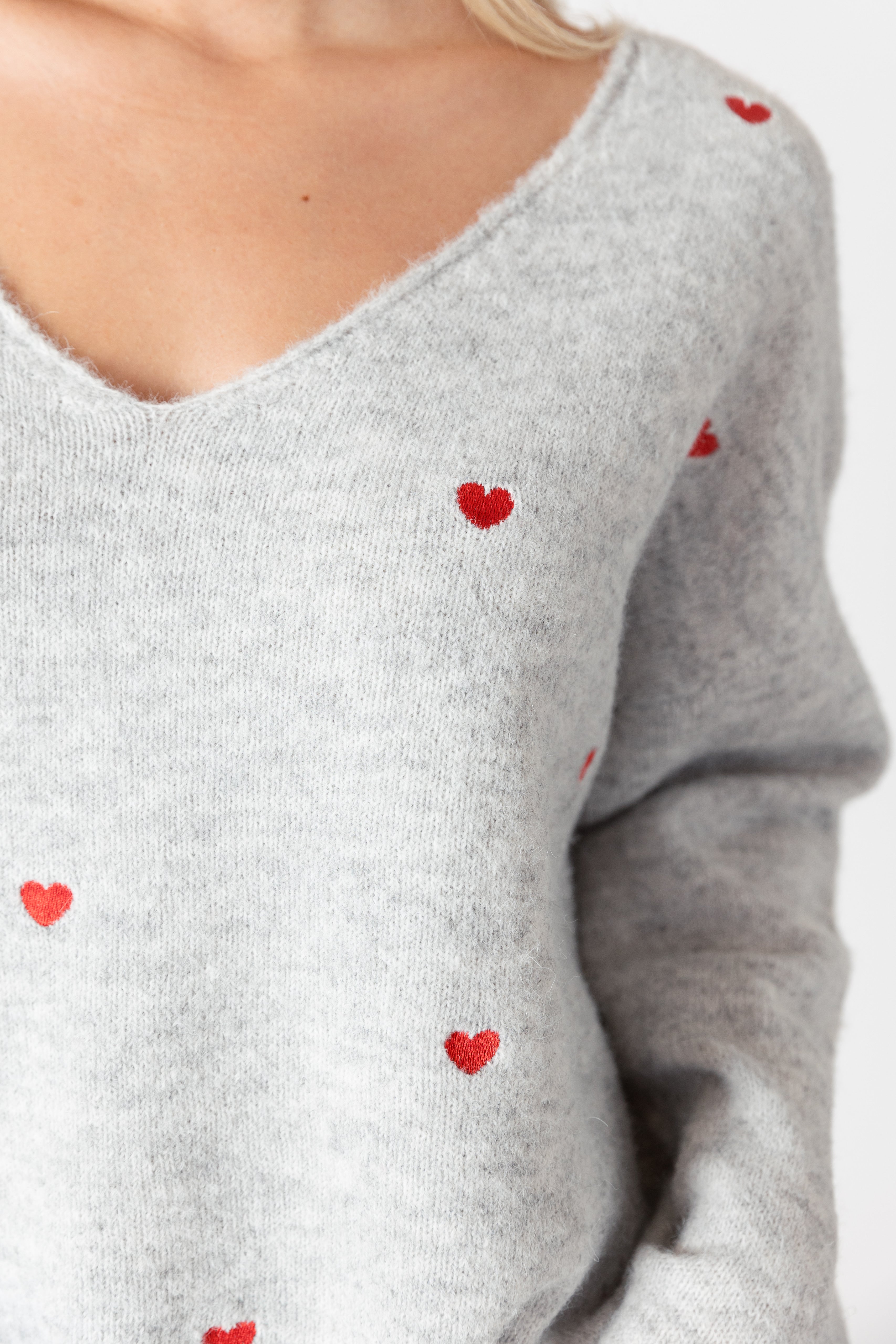 model wearing lyla & luxe luna v-neck embroidered hearts sweater, close up of embroidery