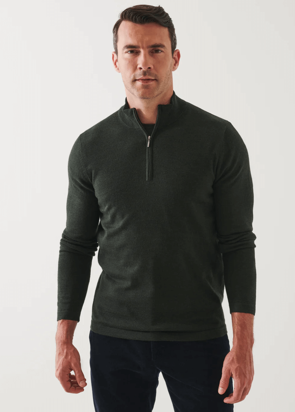 front view of the 14GG MERINO 1/4 ZIP MOCK NECK SWEATER in dark green, styled with dark pants